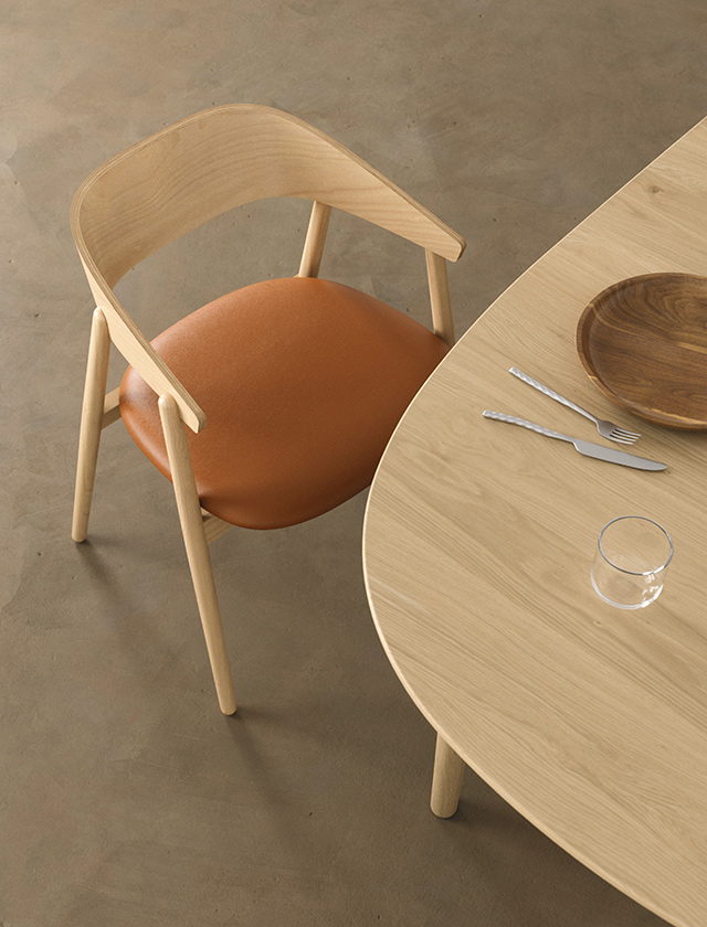 Nahaufnahme eines Andersen Furniture AC2 Esszimmerstuhls aus weiß pigmentierter Buche mit hochwertigem cognacfarbenem Ledersitz. Der Stuhl steht an einem Classic Esstisch aus massiver Eiche mit Weißöl-Finish. Die organischen Formen, natürlichen Materialien und die skandinavische Formensprache verleihen dem Essbereich eine zeitlose, elegante Atmosphäre.