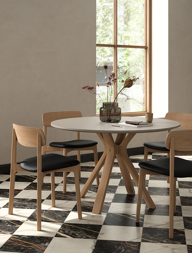 Runder Andersen Furniture Classic 290 Esstisch aus Eiche mit AC2 Chairs und schwarzen Ledersitzen in hellem Wohnambiente.
