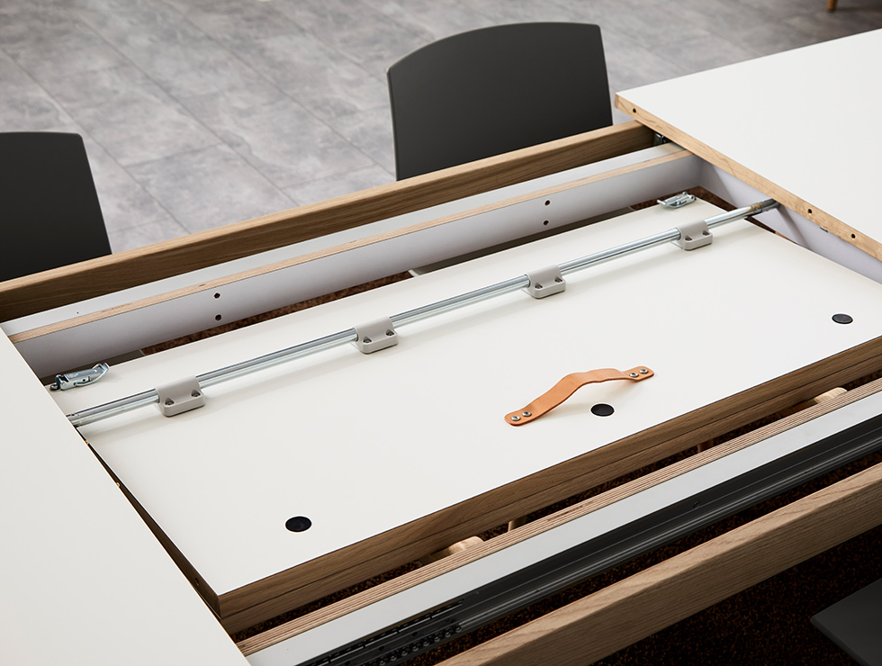 Geöffneter Andersen Furniture T3 Ausziehtisch mit weißer Laminatplatte, geseiftem Eichengestell und platzsparend im Tisch verstauter Zusatzplatte.