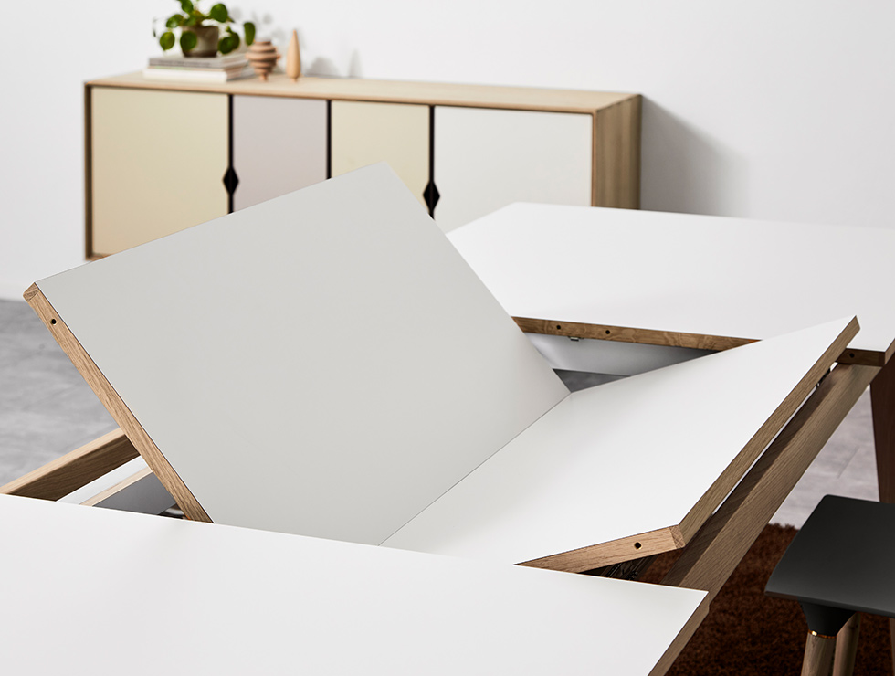 Andersen Furniture T3 Ausziehtisch mit weißer Laminatplatte und geseiftem Eichengestell beim Ausklappen der integrierten zusätzlichen Tischplatten.