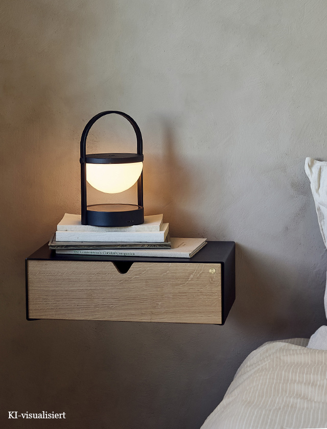 Andersen Furniture Keep Shelf als schwebender Nachttisch mit schwarzem Metallkorpus und Schublade aus Eichenholz, dekoriert mit Büchern und der tragbaren A-Flash Leuchte im Schlafzimmer.