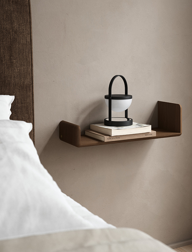 Andersen Furniture Level Shelf Wandregal aus massiver, geräucherter Eiche, als schwebender Nachttisch neben dem Bett mit schwarzer A-Flash Portable Leuchte und Büchern dekoriert.