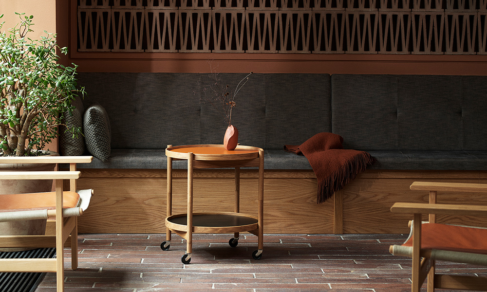Brdr. Krüger Bølling Tray Table in Clay mit Holzgestell und Rollen als eleganter Serviertisch in wohnlicher Lounge-Atmosphäre.