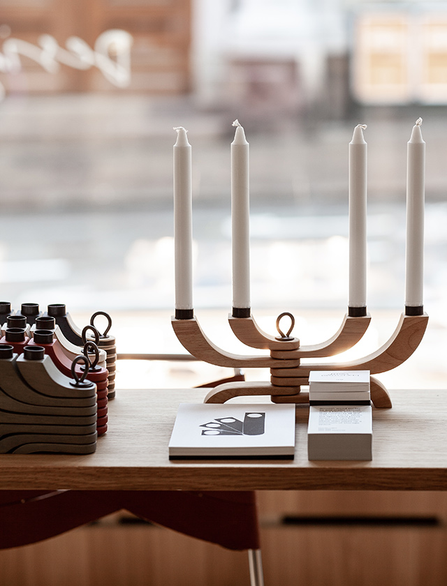 Skandinavisches Designobjekt von Design House Stockholm: Der ikonische Nordic Light Kerzenhalter aus Holz in Natur- und Rot-Tönen mit weißen Kerzen. Zeitloses nordisches Design, perfekt für moderne Wohnräume oder festliche Dekoration.