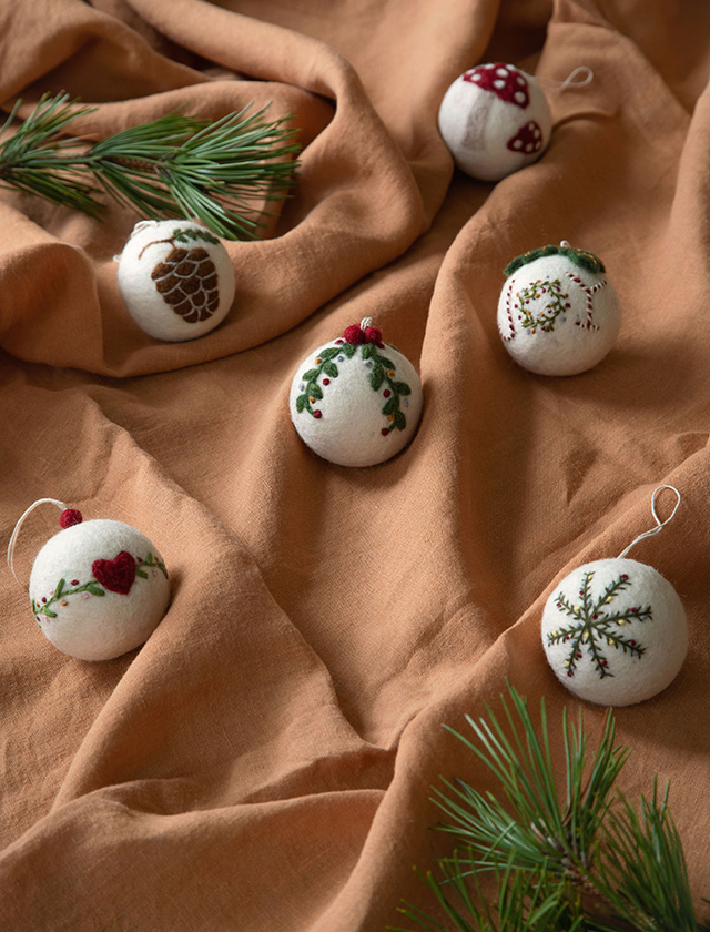 Weiße Christbaumkugeln aus Filz von Gry & Sif mit unterschiedlichen weihnachtlichen Stickereien und Motiven