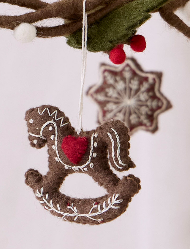 Handgefilztes Dalapferd von Gry & Sif im Gingerbread-Look mit rotem Herz und aufwendigen weißen Stickereien als Weihnachtsanhänger.
