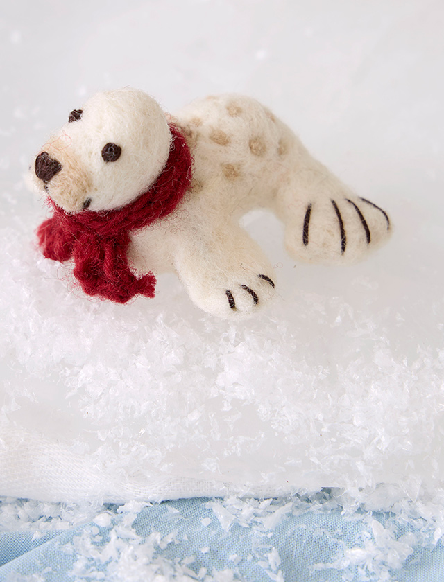 Weißes Robbenbaby aus Filz von Gry & Sif mit rotem Schal als handgefertigte Winter- und Weihnachtsdekoration
