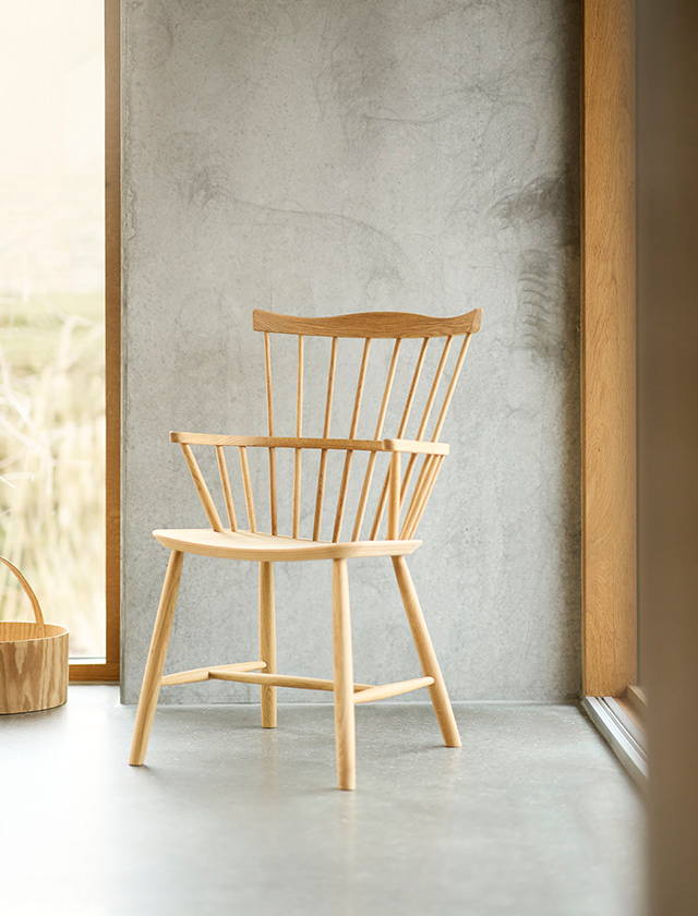 Ein stilvoll eingerichtetes Esszimmer mit den ikonischen J80 Stühlen von Jørgen Bækmark für FDB Møbler. Die Stühle in Buche und Blau-Grau kombinieren nordisches Design mit zeitloser Eleganz. Am runden Holztisch stehen frischer Tee, Brot und Kerzen – perfekt für gemütliche Momente im skandinavischen Wohnstil.