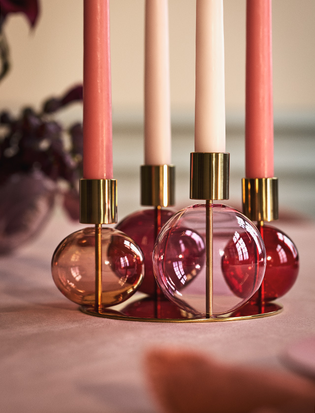 Holmegaard Bubble Kerzenhalter aus mundgeblasenem Glas mit Messing-Look in den Juwelentönen Bordeaux, Rubinrot, Pink-Saphir und Peachy-Koralle.