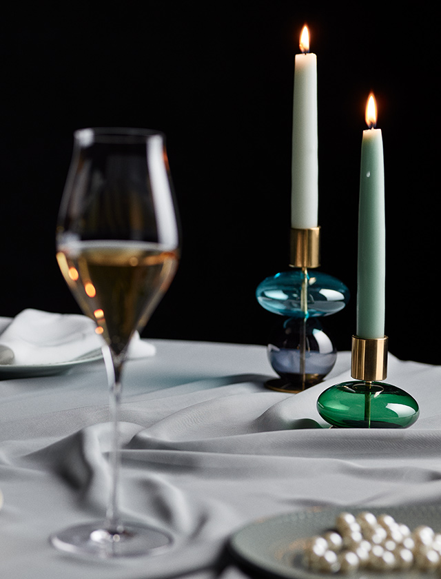 Die Holmegaard Bubble Kerzenhalter in Tiefgrün (8 cm) und Hellblau-Smoke (14 cm) bringen Vielfalt und nordische Leichtigkeit in jedes Zuhause. Ihre mundgeblasenen Glaskugeln reflektieren das Kerzenlicht auf poetische Weise, während messingfarbene Details für edle Akzente sorgen. Mit unseren handgefertigten Stabkerzen von KunstIndustrien lassen sich beide Modelle perfekt kombinieren – für stilvolle Arrangements zwischen festlichem Glanz und gemütlichem Alltagslicht.