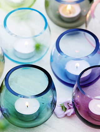 Teelichtgläser aus massivem, mundgeblasenem Glas. Hübsch dekoriert mit einzelnen Blüten. Verschiedene Blautöne, Grün und Violett.