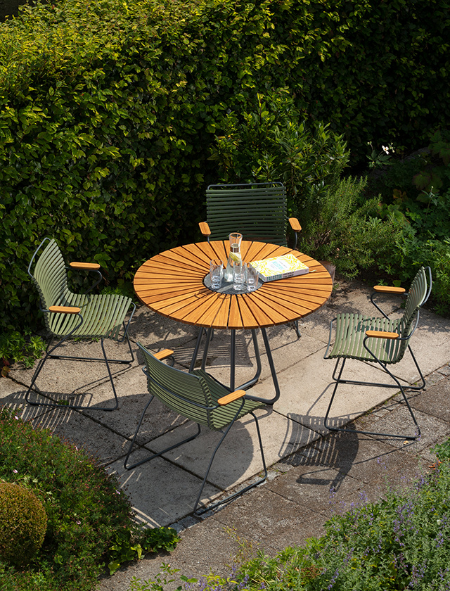 Runder HOUE CIRCLE Gartentisch aus Holz mit vier CLICK Gartenstühlen in Olive Green auf einer Terrasse im Garten