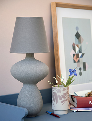 Balustre Lampe in Anthrazit von Kähler Design auf einem blauen Schreibtisch mit einer kleinen Kabell Vase in Staubrosa und einem Bild mit geometrischen Figuren in einem Bilderrahmen aus Eichenholz