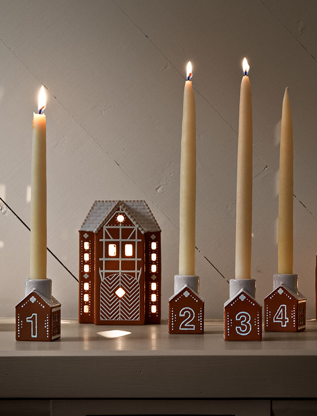 Ein geschmackvoller Weihnachtsklassiker aus handgefertigter Keramik, geformt durch Tradition: Der Kähler Gingerbread Adventskerzenhalter besteht aus vier kleinen Mini-Lebkuchenhäusern, die jeweils mit den handgezeichneten Zahlen 1 bis 4 verziert sind. Jedes Keramikhaus ist 7,5 cm hoch, detailreich dekoriert und erinnert mit seiner weißen Glasur und den filigranen Mustern an frisch gebackene Lebkuchenhäuser.