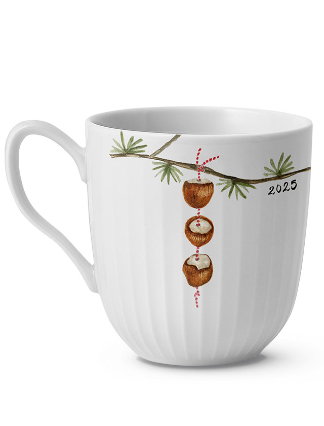 Hammershøi Christmas Weihnachtstasse 2025 aus Porzellan mit feiner Rillenstruktur, dekoriert mit einem Tannenzweig und drei hängenden Haselnusshälften an einer roten Schnur – stimmungsvolles skandinavisches Weihnachtsmotiv.