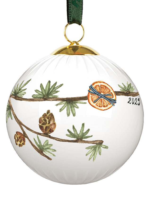 Die Hammershøi Christbaumkugel Jahrgang 2025 von Kähler Design zeigt auf der Vorderseite einen handgemalten Tannenzweig mit feiner Rillenstruktur im Hintergrund. Zwischen den sattgrünen Nadeln hängen mehrere braune Tannenzapfen, ergänzt durch eine getrocknete Orangenscheibe, die mit einer blauen Schnur befestigt ist. Rechts daneben ist in eleganter Schrift die Jahreszahl „2025“ platziert. Ein goldfarbener Metallabschluss und eine dunkelgrüne Aufhängeschlaufe verleihen der Kugel festlichen Glanz.