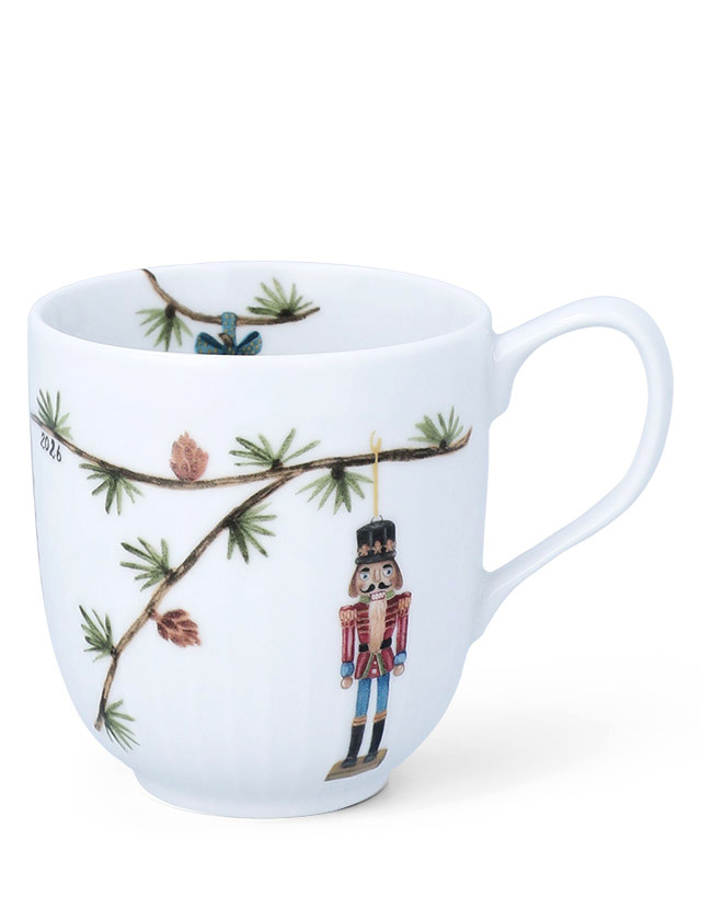 Kähler Design Hammershøi Jul Weihnachtstasse 2026 aus weißem Porzellan mit Nussknacker, Tannenzweigen und weihnachtlicher Illustration.