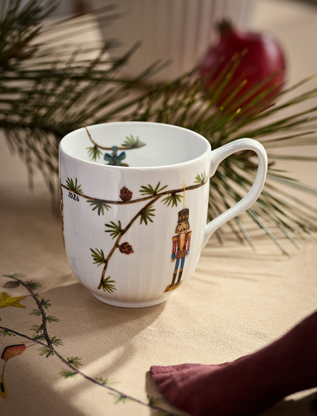 Kähler Design Hammershøi Weihnachtstasse 2026 mit Nussknacker-Motiv, Tannenzweigen und Zapfen auf festlich gedecktem Weihnachtstisch.