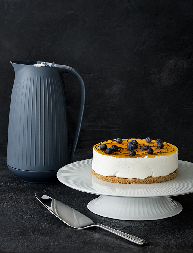 Hammershøi Torstenplatte & Tortenheber von Kähler Design und Hammershøi Isolierkanne in Anthrazit im Hintergrund. Auf der Torten- & Kuchenplatte befindet sich eine leckere Sahnetorte mit frischen Heidelbeeren.