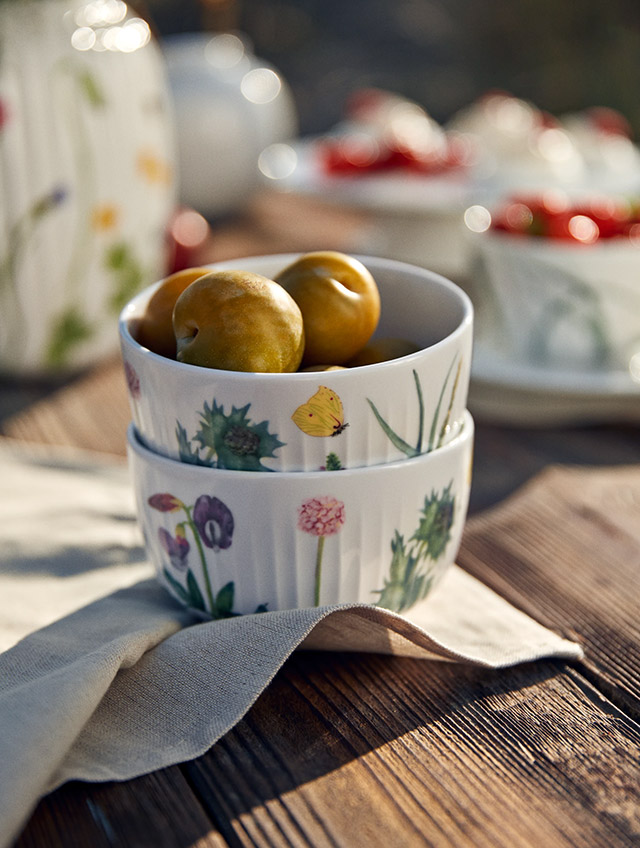 Blühende Küstenpflanzen, Muscheln und kleine Strandtiere – in sanften, gedeckten Farben auf weißem Porzellan. Die Serie Hammershøi Summer 2026 von Kähler bringt die stille Poesie eines Spaziergangs an der dänischen Küste auf den Tisch. Die feinen Aquarellmotive der Künstlerin Rikke Jacobsen scheinen dabei über die charakteristischen Rillen des von Hans-Christian Bauer entworfenen Geschirrs zu wachsen. Ein Teller für das sommerliche Frühstück, das kalte Buffet oder den Kaffee im Freien – und eine stimmige Ergänzung zu den übrigen Stücken der Serie.