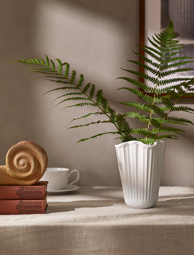 Die Kähler Hammershøi Unfold Vase ist ein zeitloses Designobjekt, das traditionelle Handwerkskunst und moderne Eleganz vereint. Inspiriert von der klassischen Hammershøi-Serie, interpretiert die Vase das ikonische Rillendesign auf frische, sanft gefaltete Weise – wie ein Keramikstoff, der sich leicht um die Form legt.