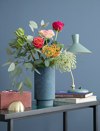 Die Kähler Kabell Vase Indigoblau in der großen Ausführung eignen sich hervorragend für größere Blumensträuße und Blumenarrangements und ziert Ihren Esstisch oder Ihr Sideboard. Rosen, Schafgarbe und Eukalyptus bilden einen schönen Kontrast zur dunklen Kabell Vase von Kähler Design