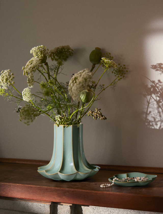 Kantarel Set aus grüner Keramikvase mit Blumen und passender Schale mit Perlen auf Holzkonsole, sanftes Licht und Schatten.