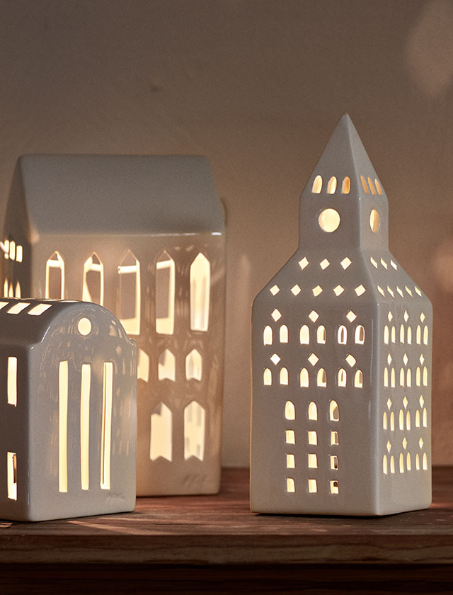Drei handgefertigte Keramik-Lichthäuser der Urbania-Serie von Kähler: der Kirchturm, die Smedje und das Manor. Die feinen Ausschnitte lassen das Kerzenlicht durchscheinen und sorgen für eine stilvolle Licht- und Schattensilhouette.