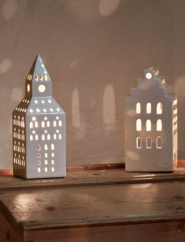 Kähler Design Hammershøi Weihnachtstasse 2025 aus feinem weißen Porzellan, verziert mit Tannenzweigen und detailreichem Schaukelpferd-Motiv, stilvoll platziert auf einem beigen Hammershøi-Tischtuch – skandinavisches Weihnachtsdesign in eleganter Ausführung.