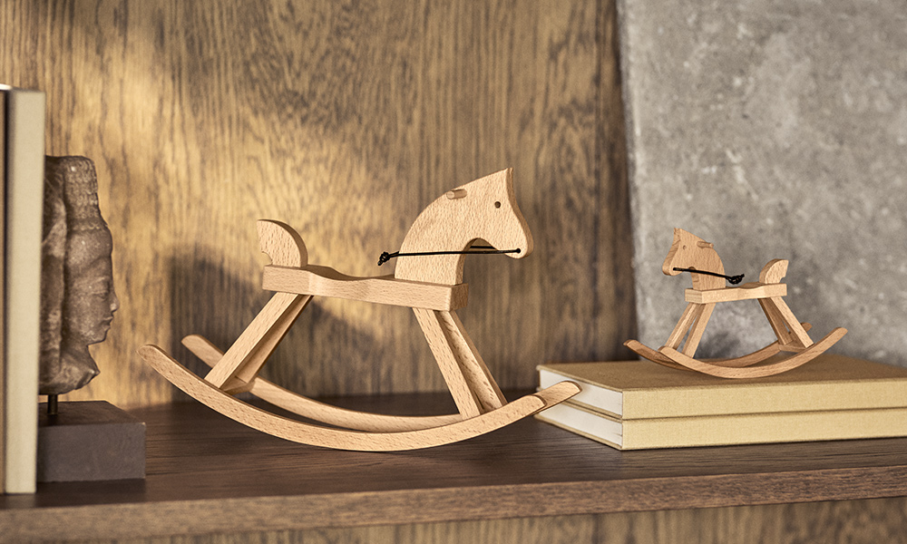 Kay Bojesen Mini-Schaukelpferd aus FSC®-zertifiziertem Buchenholz auf einem Holzbücherregal, dänischer Designklassiker seit 1936.
