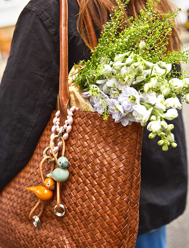 Mintfarbener Kay Bojesen Vogel Schlüsselanhänger an schwarzer Ledertasche mit Perlenhenkel, mit kleinem Kirsch-Anhänger