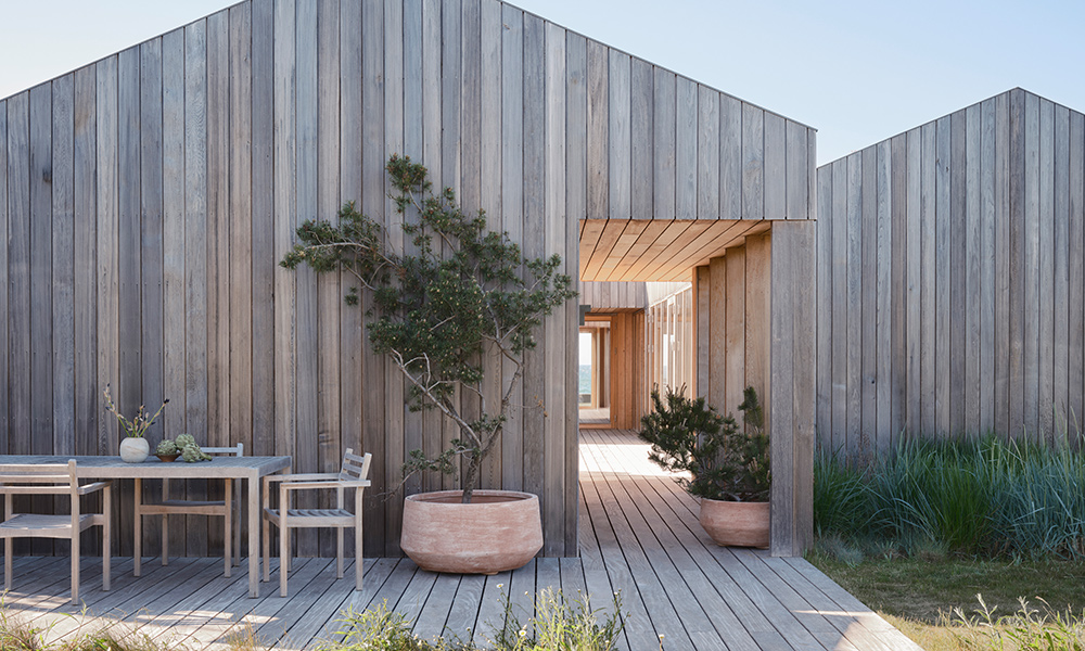 Die großen Bergs Potter Doma Pflanzgefäße in Raw Terracotta sind hier in den Größen Ø70 cm und Ø90 cm auf einer Holzterrasse vor moderner Holzarchitektur zu sehen. Die breiten Terracotta-Töpfe eignen sich ideal für kleine Bäume, Sträucher, Gräser und großzügige Bepflanzungen im Garten, auf der Terrasse oder im Eingangsbereich.