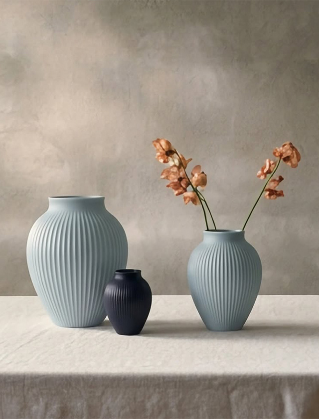 rei geriffelte Knabstrup Keramik Ripple Vasen in Ice Blue und Dark Blue matt auf hellem Tisch, eine Vase mit zarten Blüten dekoriert.