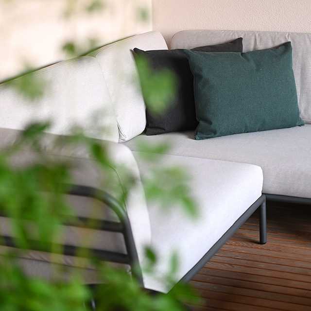 Ein Outdoor-Modulsofa mit hellem Bezugsstoff und 2 Outdoor-Kissen