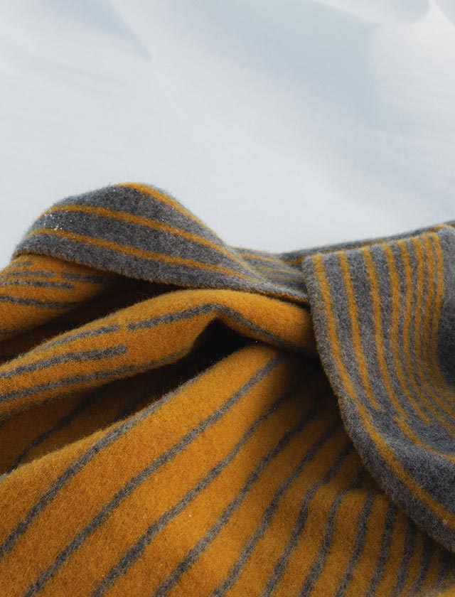 Struktur zum Verlieben: Die feine Webung der Aurora-Decke kommt in der Nahaufnahme besonders zur Geltung. Weiche Wolle, natürliche Färbung mit Kaffee, und ein raffiniertes Streifendesign machen diese Decke zu einem stilvollen Begleiter im Alltag. Jedes Stück ist ein fühlbares Statement für skandinavische Klarheit und nachhaltiges Design.