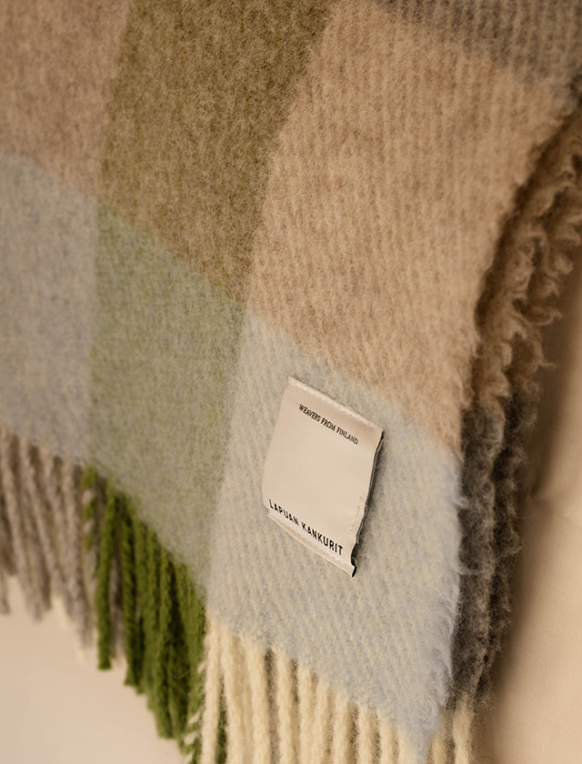Die KASKU Wolldecke von Lapuan Kankurit in der Farbvariante Light Blue Green überzeugt mit ihrem klassischen Karomuster in harmonischen Blau-, Grün-, Beige- und Grautönen. Die frische und zugleich natürliche Farbgebung verleiht jedem Raum eine ruhige, skandinavische Atmosphäre. Die hochwertige Decke ist mit weichen Fransen versehen und aus natürlichen Materialien gefertigt. Das zeitlose Design der finnischen Traditionsweberei Lapuan Kankurit passt hervorragend zu modernen, nordischen und natürlichen Wohnstilen.