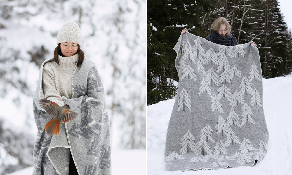 Lapuan Kankurit KUUSI Wolldecke in Light Grey-White mit Tannenbaum-Muster in einer verschneiten Winterlandschaft.