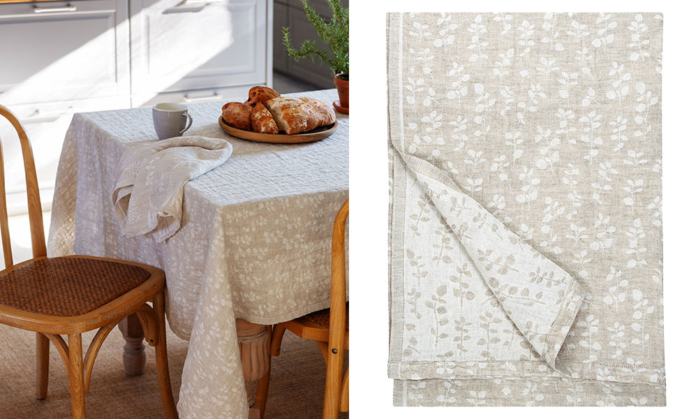 Lapuan Kankurit Tischdecke im Design MEIRAMI, gefertigt aus hochwertigem, naturfarbenem 100 % Leinen. Links im Bild ist die Tischdecke in einem hellen, freundlich eingerichteten Essbereich drapiert, dekoriert mit frischem Gebäck, einer Tasse und einem passenden Leinentuch. Das zarte, eingewebte Kräutermuster in Weiß verleiht dem Stoff eine zeitlose, skandinavische Eleganz. Rechts ist die Tischdecke im Detail zu sehen – sorgfältig umsäumt, wendbar und mit klar erkennbarer Webstruktur.