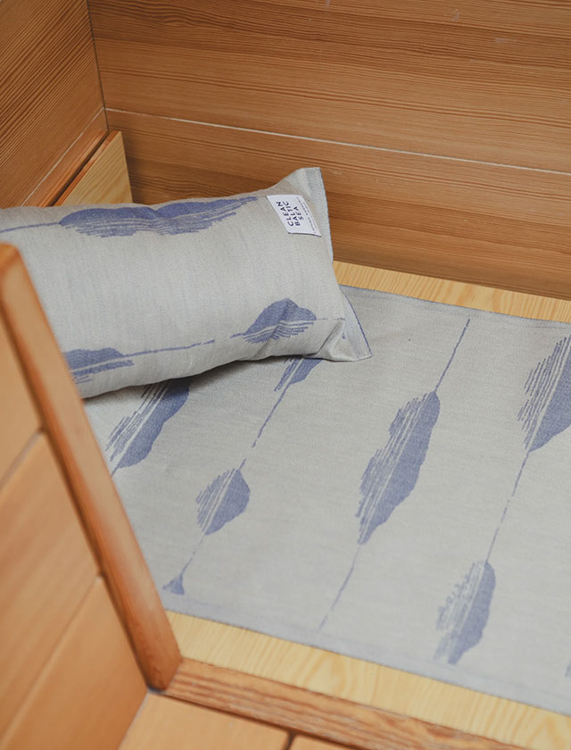 Die Merellä-Serie von Lapuan Kankurit verbindet finnisches Textildesign mit Funktionalität und Naturinspiration. Abgebildet sind das Saunakissen und die passende Sitzauflage aus Leinen in einem ruhigen Blauton, ideal für stilvolle Sauna- oder Wellnessbereiche. Das dezente, jacquardgewebte Muster basiert auf einem Entwurf von Liisa Hjelt und wurde von Elina Helenius modern interpretiert. Nachhaltig produziert in Finnland – für ein bewusstes Saunagefühl mit skandinavischer Ästhetik.