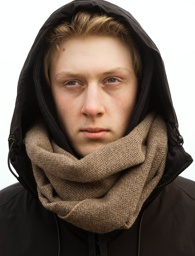 Der junge Mann trägt den Lapuan Kankurit Schal HANKI in einem eleganten Braun. Der Schal bestehen aus feinster, mulesingfreier Merinowolle, die Wärme, Leichtigkeit und luxuriösen Tragekomfort bietet. Die klaren Linien und gedeckten Farben spiegeln das typische skandinavische Design wider – ideal für Herbstspaziergänge, den Weg ins Büro oder entspannte Wochenenden in der Natur.