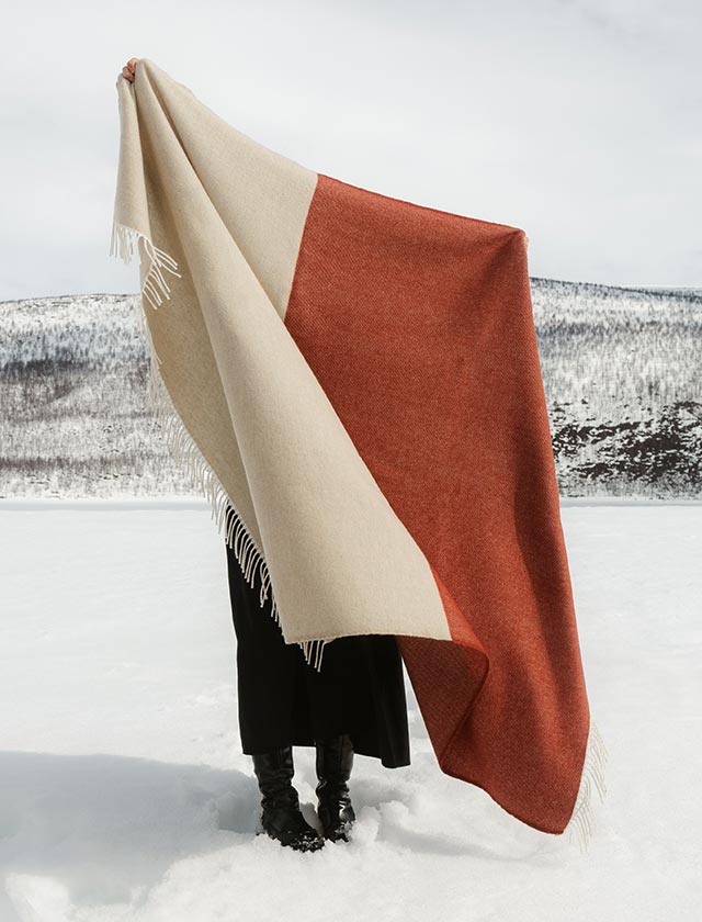 Die Lapuan Kankurit Naapuri Decke besticht durch ihr minimalistisches skandinavisches Design und die warme Farbkombination aus Beige und Zimt. Gefertigt aus feiner Merinowolle & Schurwolle in Finnland, eignet sie sich ideal als stylischer Wärmespender für Wohnzimmer, Terrasse oder Outdoor-Ausflug. Das zeitlose Blockmuster harmoniert perfekt mit modernen und naturnahen Einrichtungskonzepten.