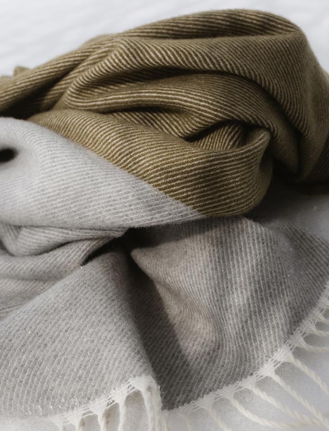 Die Naapuri Decke aus feiner Merino- und Schurwolle in Grau-Oliv – weich, atmungsaktiv und mit elegantem Streifenmuster