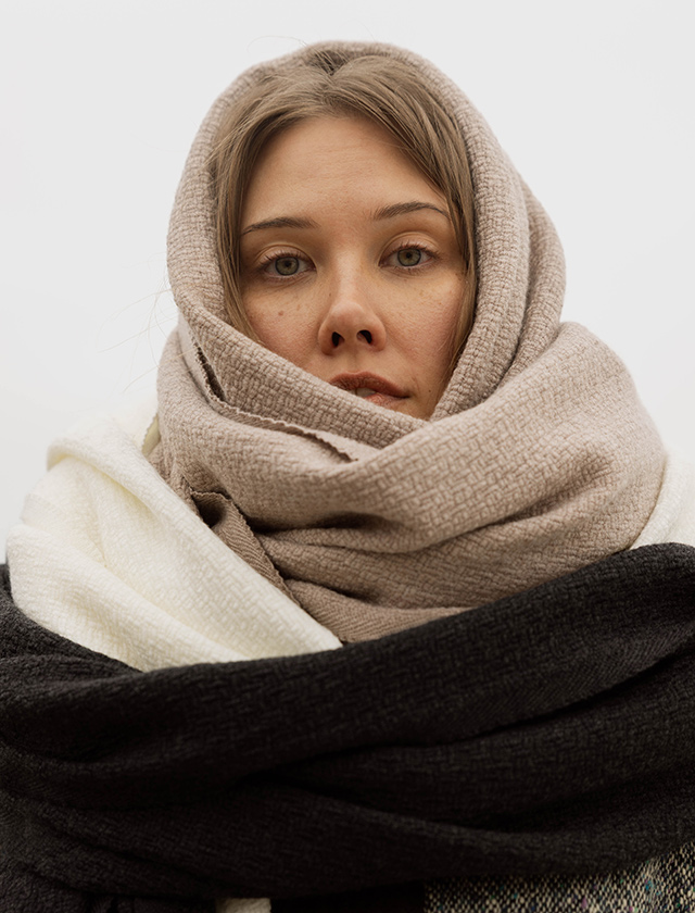 Tuula Schal von Lapuan Kankurit aus weicher Merinowolle, entworfen von Elina Helenius, in dunklen Farbtönen Black Heather und Black Grey getragen im natürlichen Outdoor-Ambiente.