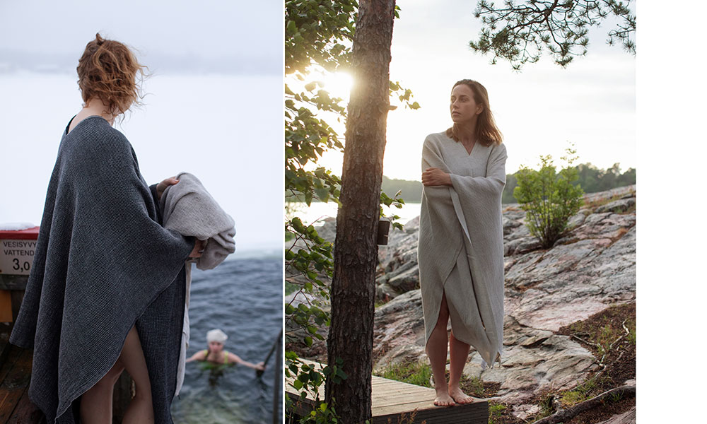 Terva Poncho von Lapuan Kankurit, gefertigt aus einer hochwertigen Leinen-TENCEL™-Mischung. Links ist eine Frau zu sehen, die den schwarzen Poncho nach einem erfrischenden Bad im See um die Schultern trägt, während sie ein weiteres Tuch in den Händen hält. Im Hintergrund steigt eine weitere Person aus dem Wasser. Rechts steht eine Frau im hellgrauen Terva Poncho barfuß auf einem Felsen am Seeufer, umgeben von Bäumen und weichem Abendlicht. Die Szene vermittelt die klare, natürliche Ästhetik Skandinaviens und betont die Vielseitigkeit, den Komfort und die nachhaltige Herstellung des Ponchos in Finnland.