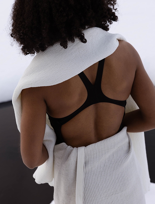 Lapuan Kankurit Kaisla und Terva Handtücher in Weiß, gezeigt an einer Person von hinten in heller, reduzierter Umgebung.