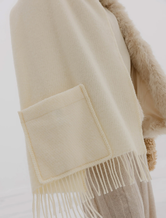Lapuan Kankurit UNI Pocket Shawl in Weiß mit aufgesetzter Tasche und Fransen, getragen als wärmender Wollschal bzw. Poncho