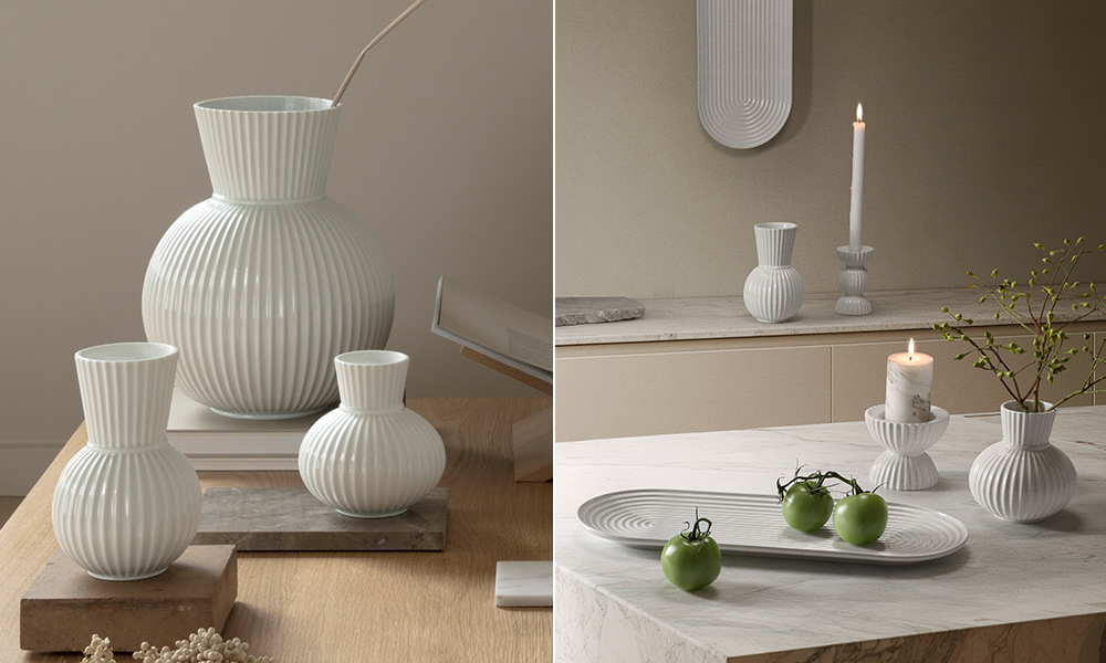 Stilvolle Wohnszene mit geriffelter, weißer Porzellan-Kollektion der Lyngby Porcelæn Tura-Serie: Links sind mehrere Vasen in unterschiedlichen Größen auf einem Holztisch arrangiert. Rechts ergänzen Kerzenhalter und eine ovale Servierplatte das skandinavische Setting auf einer Marmorplatte – dekoriert mit Kerzen, Zweigen und grünen Früchten für einen ruhigen, minimalistischen Look.