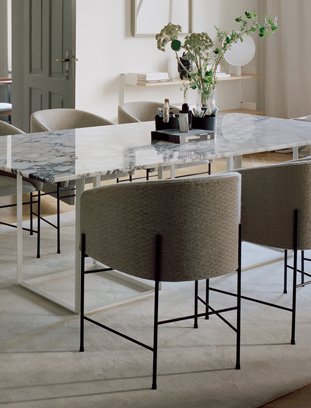 Eleganter Regatta Stuhl aus geölter Eiche mit Lederpolster in Cognac am ovalen Salon Tisch aus Holz in modernem Esszimmer mit Kamin und Tulpenvase.