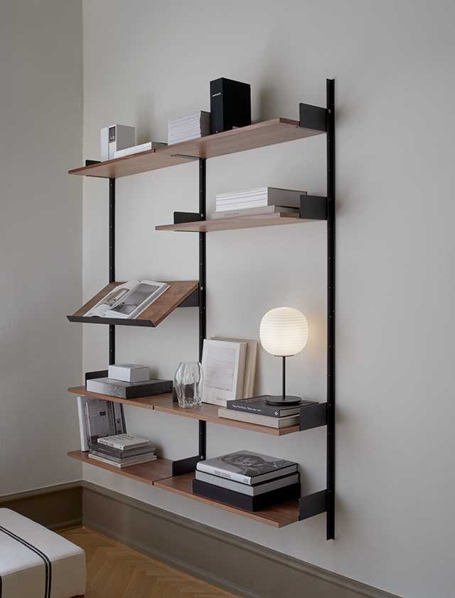 New Works - Living Shelf - Regal mit 7 Fachböden in Nussbaumfurnier, einer Magazinablage und schwarzen 3 Wandprofilen 1900. Maße: 1900 mm Höhe, 1635 mm Breite, 305 mm Tiefe. Fachböden sind in der Höhe verstellbar.