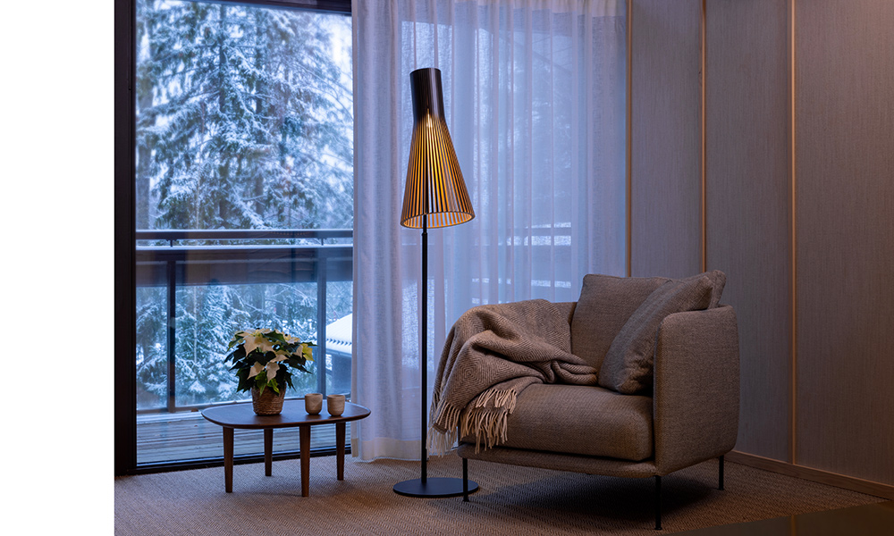 Skandinavisches Wohnambiente mit der Secto Design Stehleuchte Secto 4210 in schwarzer Birke. Stilvolle Einrichtungsidee für gemütliche Winterabende – modernes Lichtdesign trifft auf natürliche Materialien.